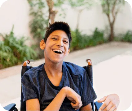 Smiling child in a wheelchair wearing a black t-shirt, looking at the camera, physiotherapy for cerebral palsy