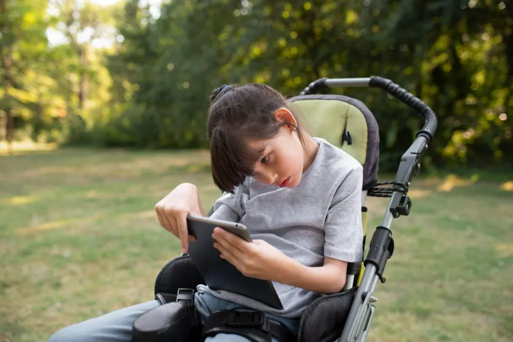 Child in wheelchair using tablet as part of muscular dystrophy support activities