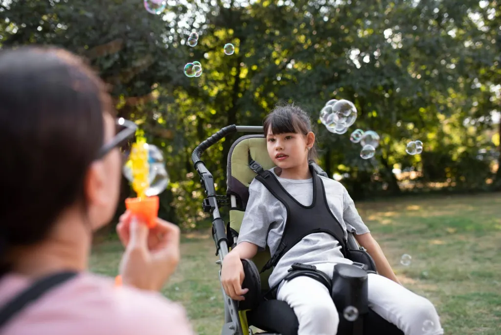 Girl in wheelchair playing with bubbles during muscular dystrophy support therapy