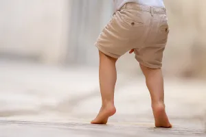 Child toe walking outdoors in beige shorts, showing early signs addressed by toe walking physiotherapy