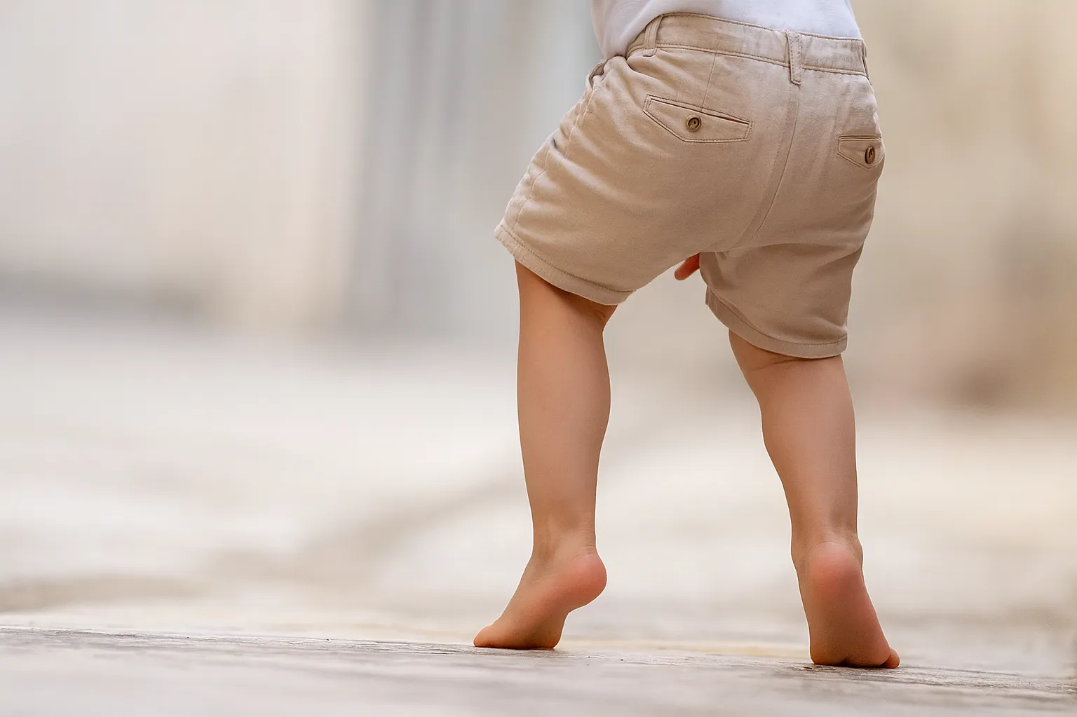 Child toe walking outdoors in beige shorts, showing early signs addressed by toe walking physiotherapy