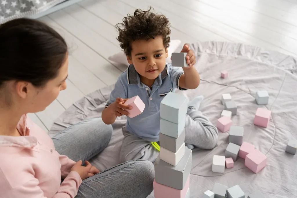 Young child practicing motor skills by stacking blocks with guidance during developmental delay therapy session