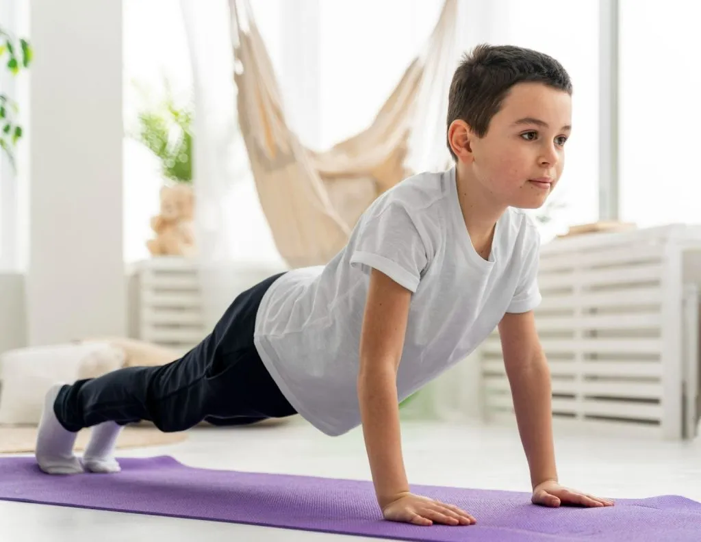 Child practising core strength exercise during physical activity for kids session on a yoga mat