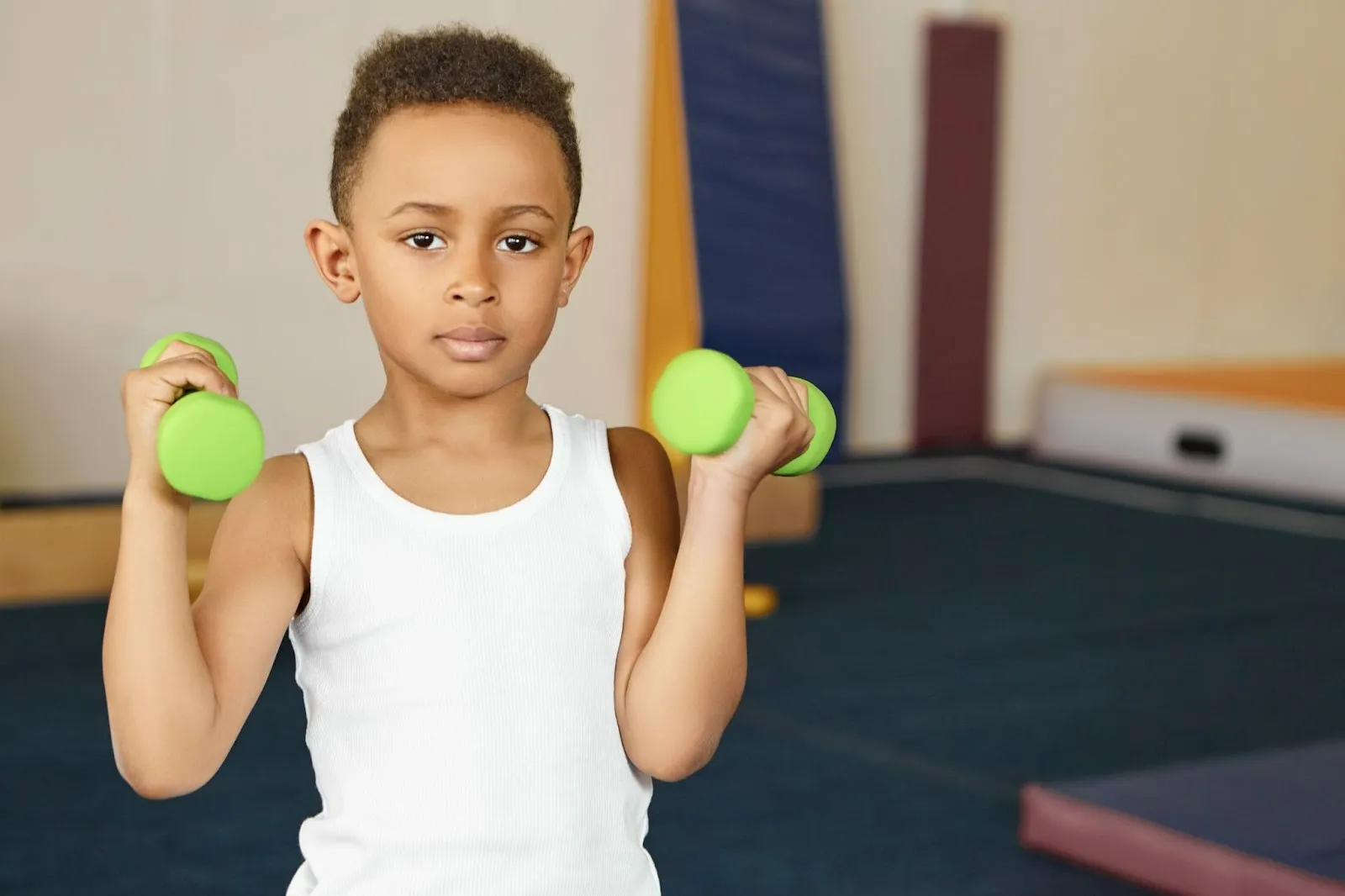 Child building upper body strength with light weights as part of physical activity for kids program