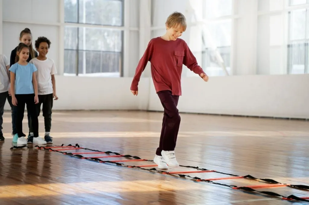 Child walking through agility ladder during physiotherapy session to build balance and coordination for poor coordination in child