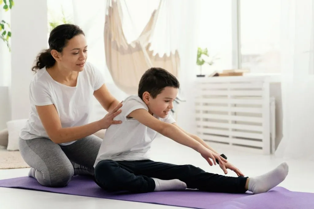 Children’s physiotherapist guiding a boy through stretching exercises to support motor development – signs your child needs physiotherapy