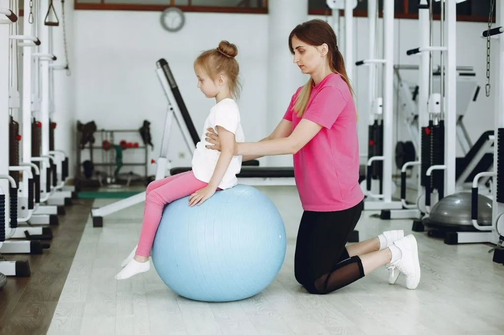 Paediatric physiotherapist helping a young child improve balance and posture on a therapy ball – signs your child needs physiotherapy