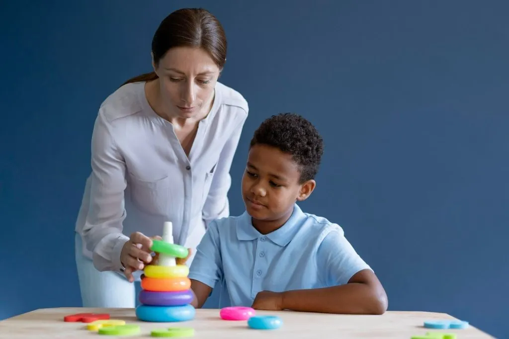Therapist guiding child in play based learning in early childhood using educational stacking game